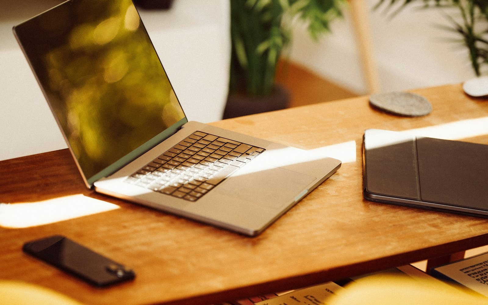 A laptop, tablet and phone arranged on a warm wooden product workspace.